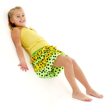 A cute little girl leaned against a white wall. Cyclorama in studio. Isolated on a white background.
