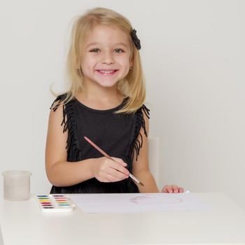 Joyful little girl draws with a brush and paints. The concept of children's creativity.