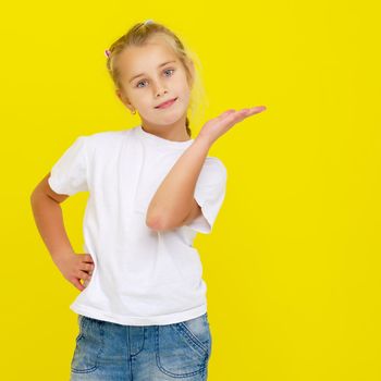 Emotional little girl in a clean white T-shirt. The concept can be used to advertise goods and services, whose logo can be printed on the surface of the shirt.On a yellow background.