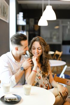 Young european man hugging woman at cafe, ,sitting near cups of coffee. Concept of positive emotions, feelings and resting on lunch.