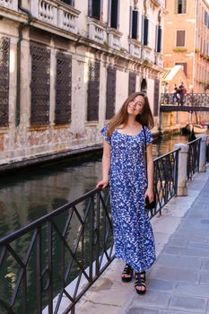 Young female tourist standing near banister in Venice, Italy. Concept of last minute tours to Europe and romantic venetsian street.