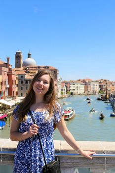 Young girl standing in Venice background, Italy. Concept of last minute tours to romantic Europe and amazing summer trip.