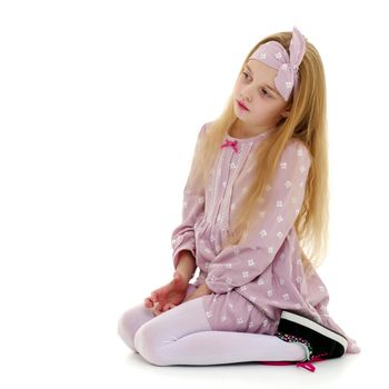 Beautiful little girl kneels in the studio on a white background. The concept of beauty and fashion, children's emotions. Isolated.