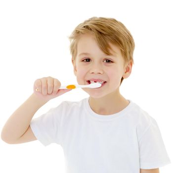 A cute little boy is brushing his teeth with a toothbrush. On a pure white T-shirt in which he is dressed you can make an advertising inscription. The concept of children's health, medicine. Isolated on white background.