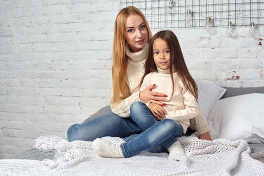 Happy loving family. Mother and her daughter child girl playing and hugging on bed