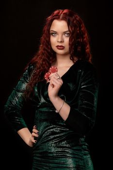 Young beautiful redheaded woman with chips in her hands is posing for the camera, over black. Win casino holdem poker slots
