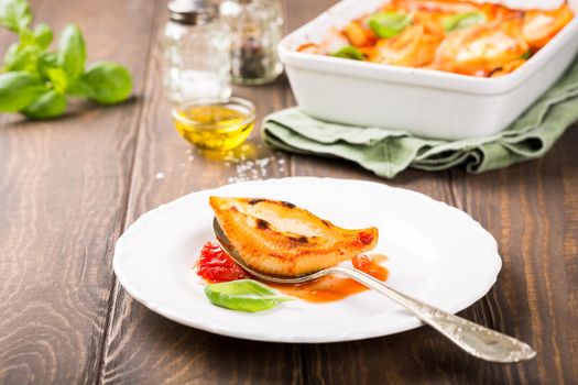 Italian pasta Conchiglioni Rigati stuffed with three sorts of cheese and and baked in tomato sauce. Healthy food concept with copy space.