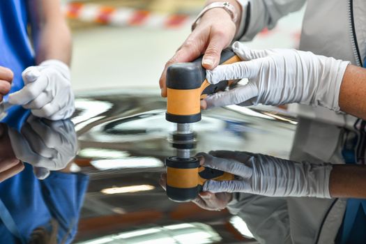 Operator holds a polisher in the hand for scratch on a car