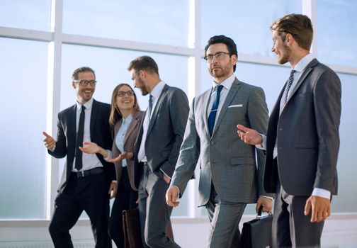 Confident businessman with colleagues strolling in the office