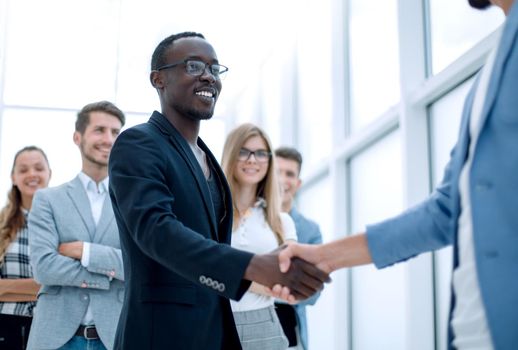 businessmen greet each other. Colleagues stand in the background