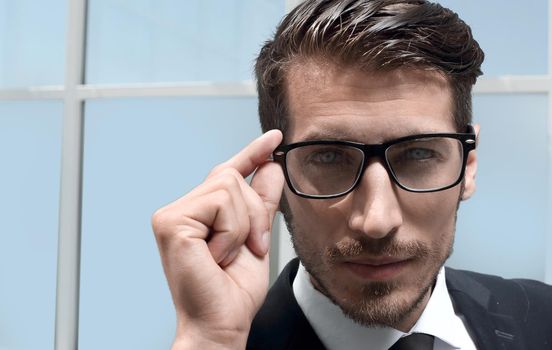 young successful businessman with a serious face stands in the office in a business suit