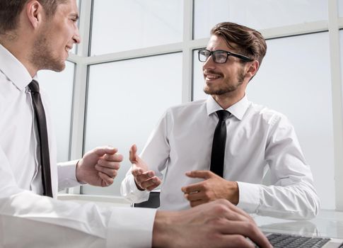 Two businessmen are sitting in the office and discussing the conclusion of a new deal