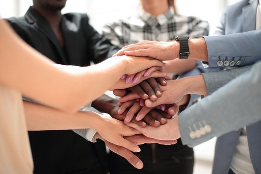 Large group of people standing in circle and stacking hands. Together making a successful team