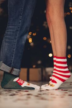 Cropped photo of legs of man and woman in warm Christmas socks. Holiday concept