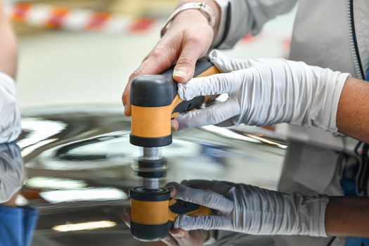 Operator holds a polisher in the hand for scratch on a car