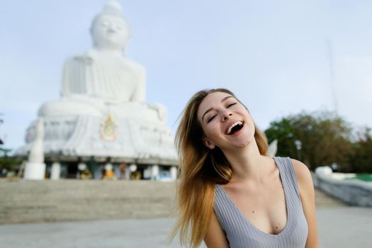 Young nice girl standing with Buddha statue in Phuket, Thailand. Concept of traveling to Asia and buddhism landmark.