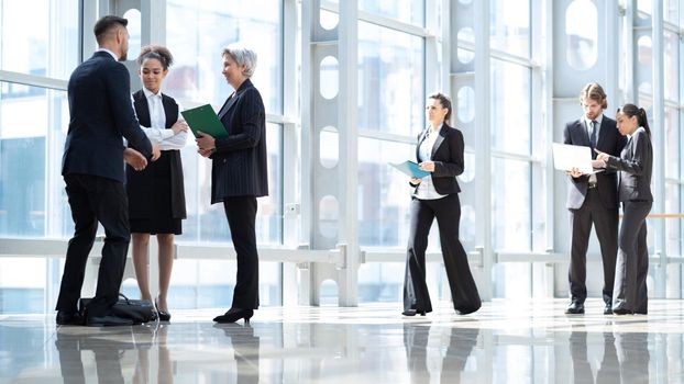 Business people talking about documents in office lobby of modern building