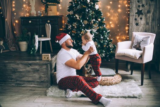 Happy young father playing with his cute kid on Christmas eve at home. Holiday concept