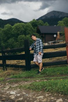 Guy by a fence of pasture enjoying nature, posing at camera