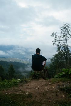 Guy top of a hill enjoying view of nature, rear view.