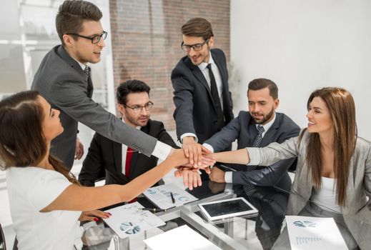 group of employees folded their hands together over the Desk. concept of success
