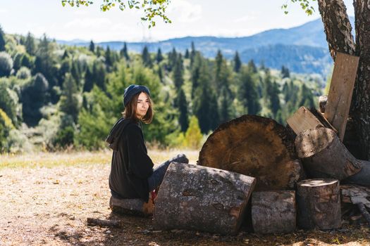 Woman next to logs of cut wood