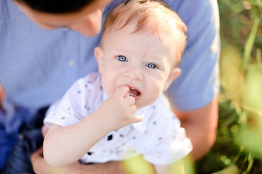 Closeup portrait of little male baby on father blue t shirt background. Concept of childhood.