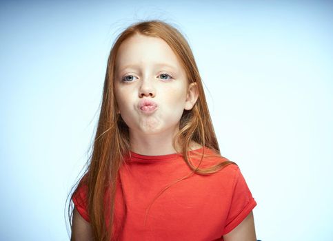 red-haired girl in a red t-shirt posing childhood. High quality photo