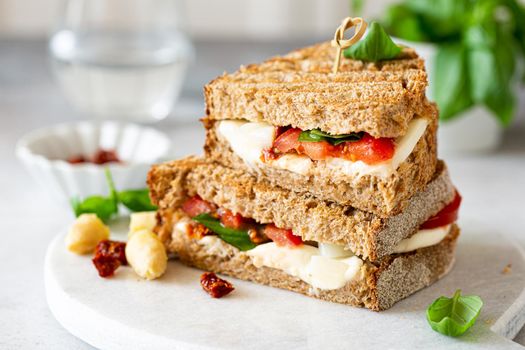 Delicious toast with white asparagus, tomatoes, mozzarella, sun-dried tomatoes and basil on white marble board. Healthy food concept with copy space.