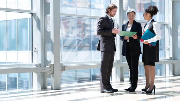 Business people talking about documents in office lobby of modern building