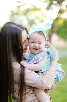 Young caucasian mother holding little daughter in garden. Concept of motherhood and child.