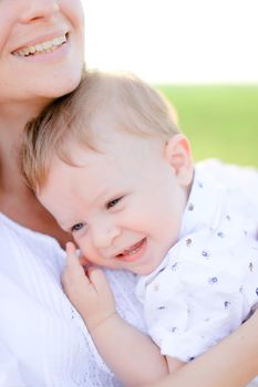 Closeup portrait of young mother holding little baby in green background. Concept of motherhood and children, new life.