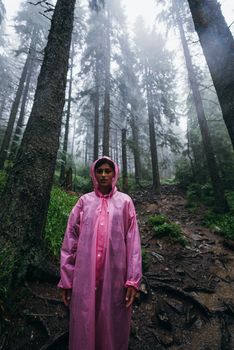 woman in raincoat walking by rainy forest