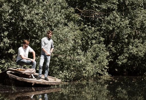 two friends are fishing on the lake in the early morning . lifestyle