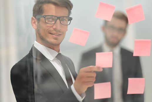 serious employee reads a sticker-note on the office Board.business concept