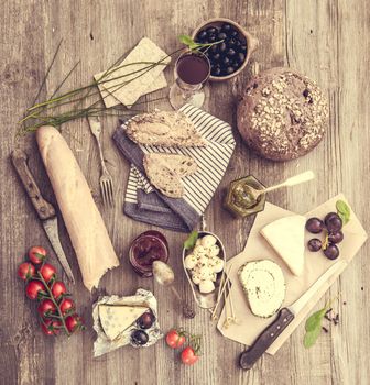 Cheese, wine and other food ingredients on a wooden table. French snacks on a wooden background.