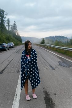 Tourist woman walking on a highway in the mountains, alone