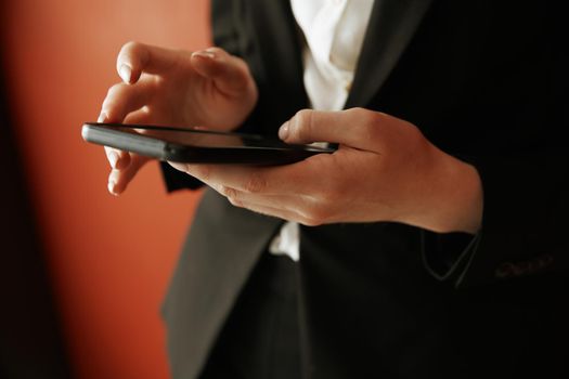 Young adult woman using smartphone next to the red wall