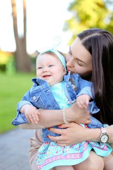 Young brunette woman holding little daughter wearing jeans jacket. Concept of motherhood and children.