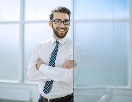 smiling businessman standing near the office window.business people