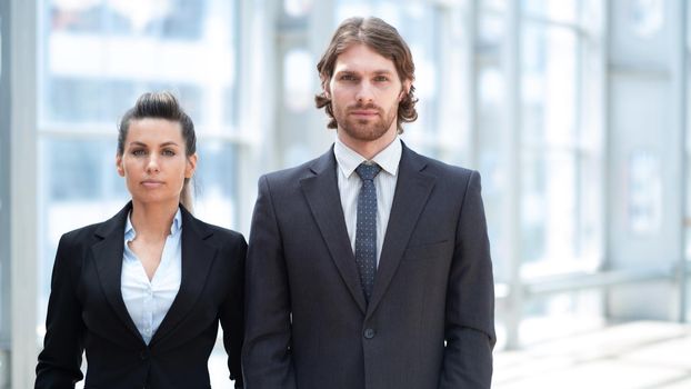 Portrait of two business people man and woman standing in lobby of modern building