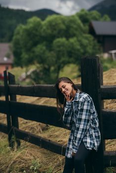 A young attractive Caucasian female stand by a fence and posing at camera