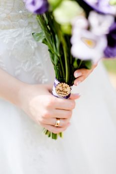 Closeup bridal hands keeping violet bouquet of flowers. Concept of wedding photo session and floristic art.