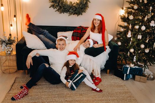 Close-up portrait of a happy family sitting on a sofa near a Christmas tree celebrating a holiday.