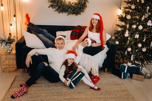 Close-up portrait of a happy family sitting on a sofa near a Christmas tree celebrating a holiday.