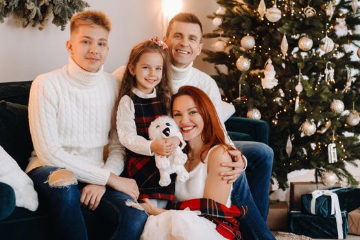 Close-up portrait of a happy family sitting on a sofa near a Christmas tree celebrating a holiday.