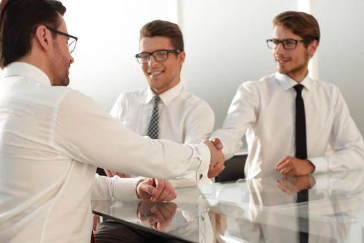 business partners shake hands while sitting at the table.business concept