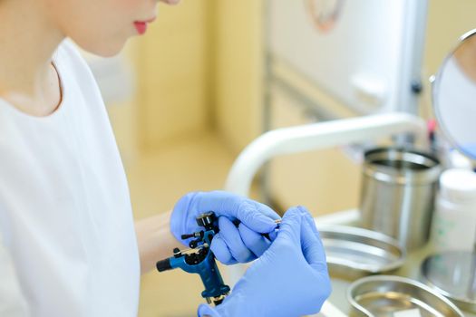 Closeup hands in blue latex gloves inserting needle into microblading machine at beauty salon. Concept of cosmetology equipment for permanent makeup.