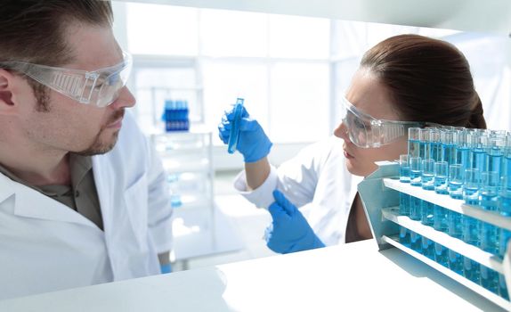 close up.two researchers look at the liquid in the test tube.science and health