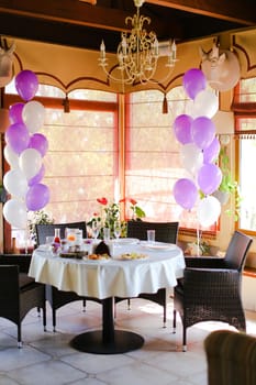 Food on table at cafe and white violet ballons. Concept of preparations for birthday.